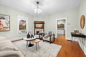 Interior space with a stone fireplace, light hardwood / wood-style flooring, a notable chandelier, and cooling unit