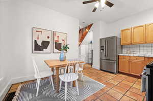 Kitchen featuring stainless steel appliances, tile countertops, light tile patterned floors, ceiling fan, and backsplash