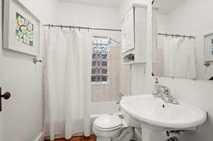 Full bathroom with sink, toilet, and shower / bathtub combination with curtain