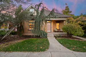 View of property hidden behind natural elements featuring a porch and a yard