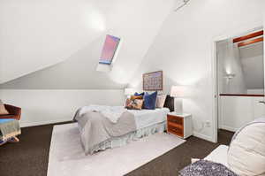 Carpeted bedroom with vaulted ceiling with skylight