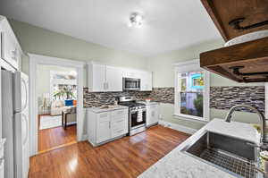 Kitchen with white cabinetry, sink, dark hardwood / wood-style floors, and stainless steel appliances