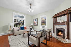 Living room with hardwood / wood-style floors, plenty of natural light, cooling unit, and a notable chandelier