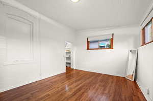 Empty room featuring wood-type flooring and brick wall