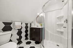 Bathroom featuring walk in shower, vanity, toilet, and lofted ceiling