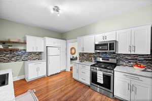 Kitchen featuring light hardwood / wood-style flooring, appliances with stainless steel finishes, and white cabinets