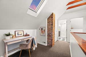 Carpeted home office with lofted ceiling and built in desk