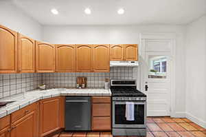 Kitchen featuring tile counters, stainless steel appliances, sink, and backsplash