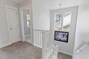 Hallway featuring light colored carpet