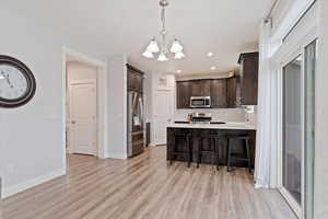 Kitchen with kitchen peninsula, light hardwood / wood-style floors, appliances with stainless steel finishes