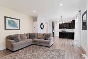 Living room featuring light wood-type flooring, a dining area chandelier