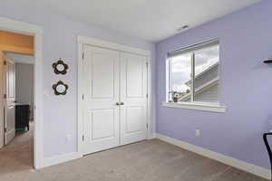 Bedroom with light carpet and a closet