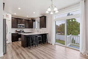 Kitchen with kitchen peninsula, light wood-type flooring, and appliances with stainless steel finishes