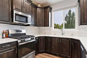 Kitchen featuring light hardwood / wood-style flooring, sink, dark brown cabinetry, and stainless steel appliances