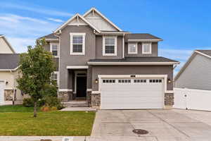 Craftsman inspired home featuring a garage and a front lawn