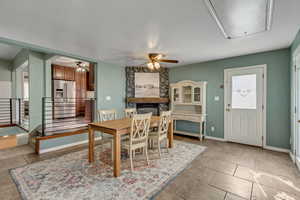 Family room featuring a stone fireplace, light tile patterned floors, and ceiling fan