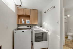 Washroom with light tile patterned floors and washer and clothes dryer