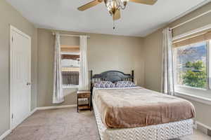 Bedroom with light carpet, multiple windows, and ceiling fan