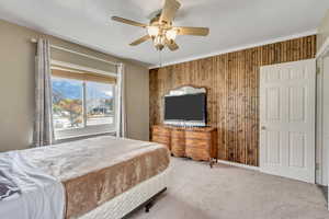 Bedroom with wood walls, ceiling fan, and carpet