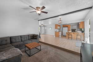 Living room featuring ceiling fan, a textured ceiling, and light hardwood / wood-style floors