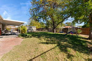 View of yard featuring a playground, a storage unit, and a patio