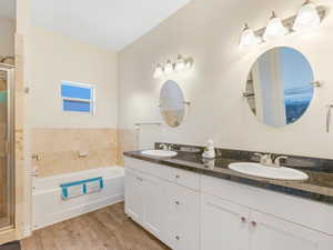 Bathroom featuring wood-type flooring, a tub to relax in, and vanity