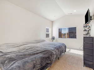 Bedroom with vaulted ceiling and light carpet