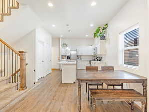 Kitchen with white cabinets, light wood-type flooring, stainless steel appliances, and decorative light fixtures