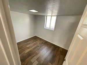 Basement with a textured ceiling and dark hardwood / wood-style floors