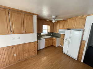 Kitchen with light hardwood / wood-style flooring, ceiling fan, white appliances, and sink