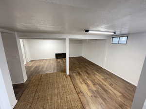 Basement featuring a textured ceiling and dark hardwood / wood-style flooring