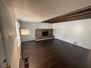 Unfurnished living room featuring a textured ceiling, a fireplace, and dark hardwood / wood-style floors