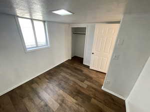 Unfurnished bedroom with dark wood-type flooring, a closet, and a textured ceiling