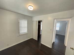 Unfurnished bedroom with dark hardwood / wood-style flooring and a closet