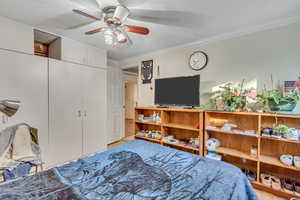 Bedroom with ceiling fan, a textured ceiling, light hardwood / wood-style flooring, and crown molding