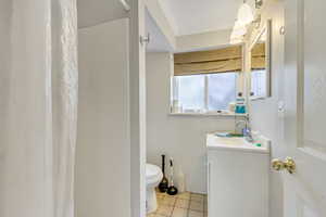 Bathroom with vanity, tile patterned floors, toilet, and ornamental molding