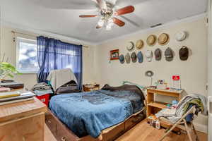 Bedroom with wood-type flooring, ceiling fan, a textured ceiling, and ornamental molding