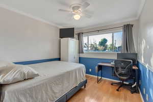 Bedroom featuring ornamental molding, light wood-type flooring, and ceiling fan