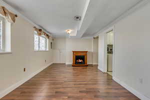 Unfurnished living room featuring dark wood-type flooring and ornamental molding