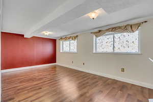 Spare room with wood-type flooring and beam ceiling