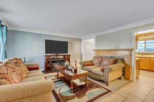 Living room featuring sink, light tile patterned floors, and ornamental molding