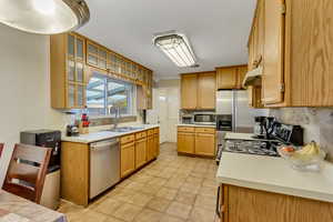 Kitchen featuring stainless steel appliances, light tile patterned floors, sink, and decorative backsplash