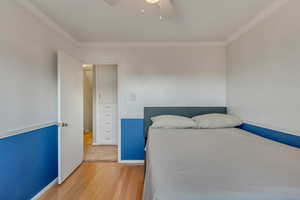 Bedroom with hardwood / wood-style floors, ceiling fan, and crown molding