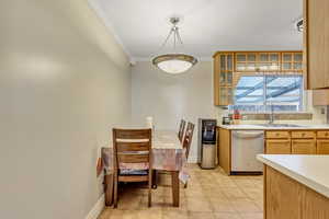 Kitchen with sink, light tile patterned floors, ornamental molding, stainless steel dishwasher, and pendant lighting