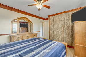 Carpeted bedroom with ornamental molding and ceiling fan