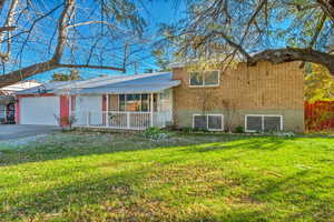 View of front of property featuring a garage, a porch, and a front yard