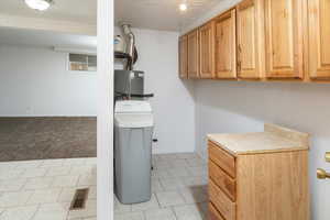 Laundry room with water heater, a textured ceiling, and light carpet