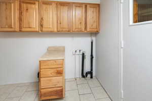 Washroom featuring washer hookup, cabinets, and light tile patterned floors