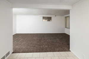 Carpeted spare room featuring a textured ceiling and crown molding