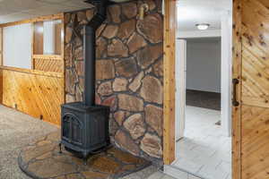 Room details featuring wood walls, a drop ceiling, a wood stove, and carpet